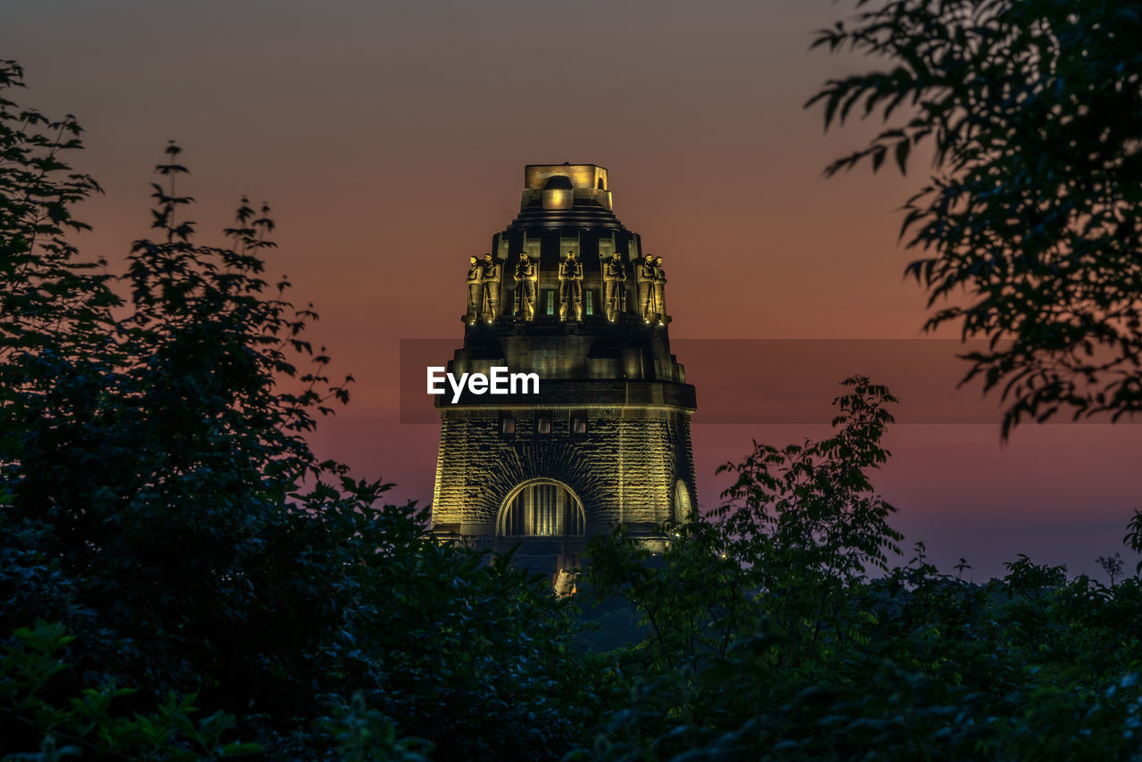 Low angle view of illuminated building against sky at sunset