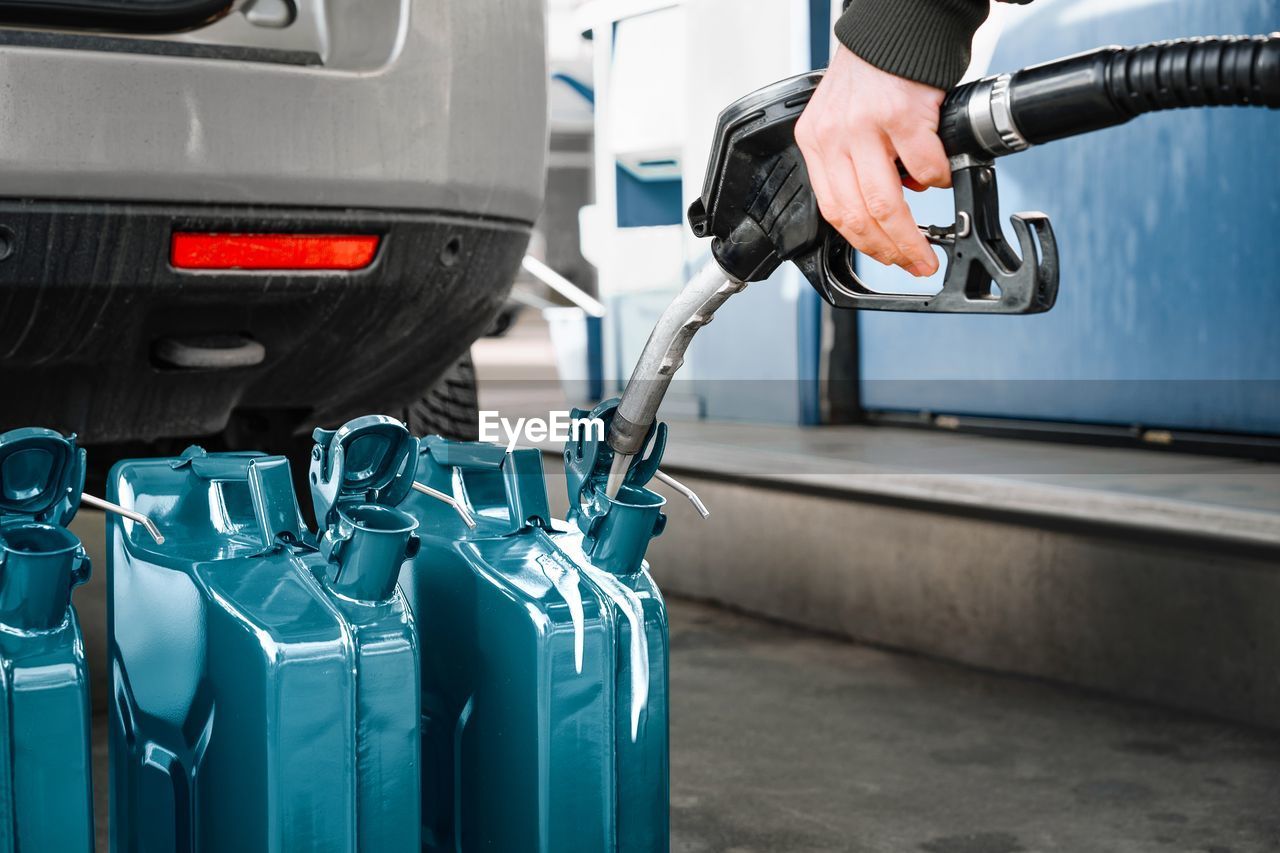 Person filling oil canisters at gas station. fuel crisis concept