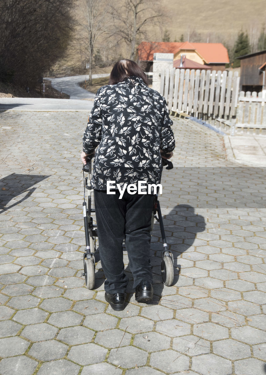 REAR VIEW OF PEOPLE WALKING ON STREET