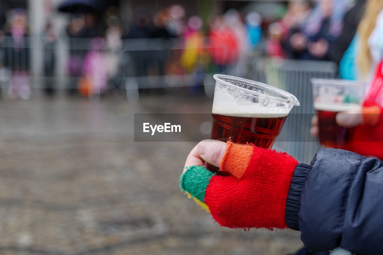 Midsection of person holding beer glass against blurred background