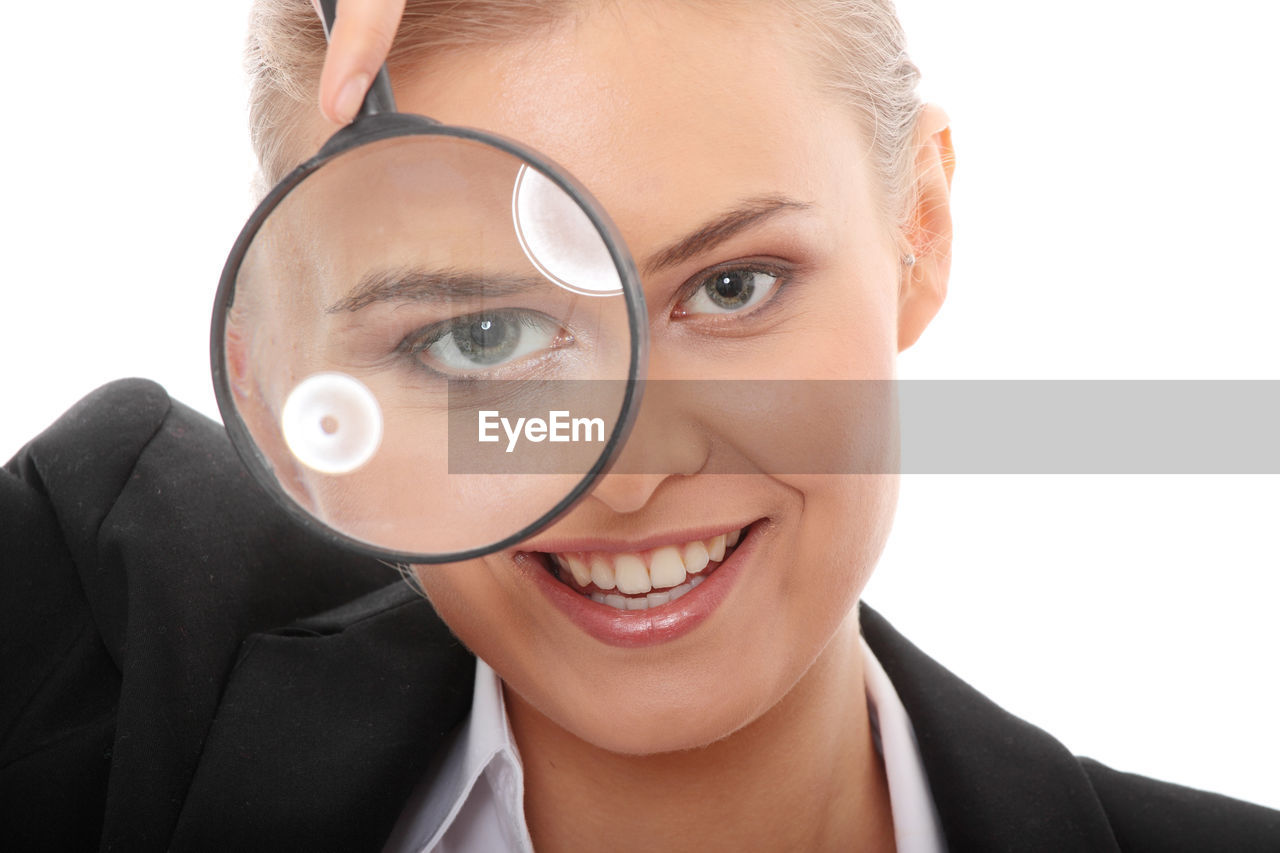 Close-up of businesswoman with magnifying glass against white background