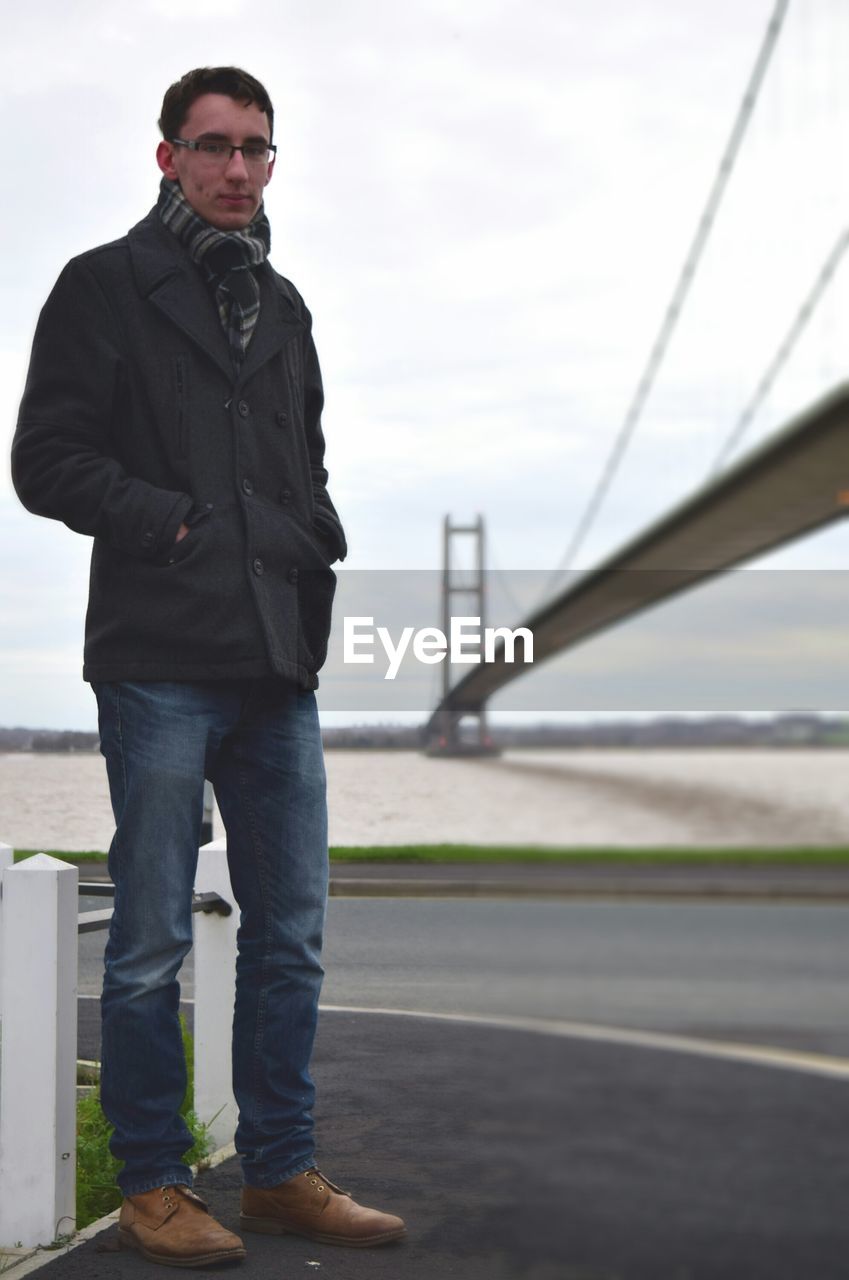 Young man standing by suspension bridge