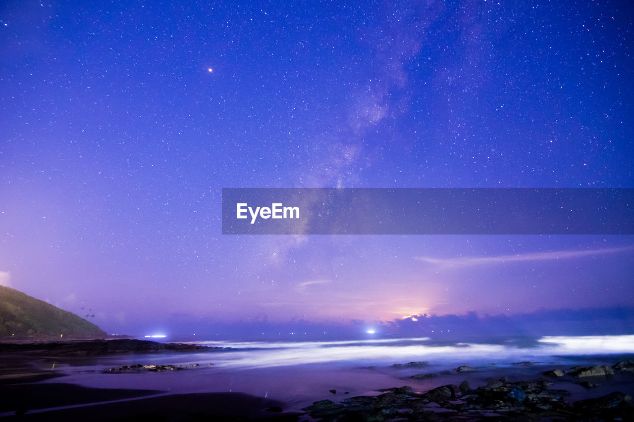 Scenic view of sea against star field at night