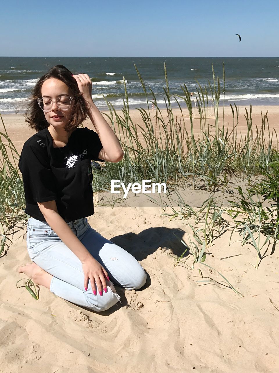 YOUNG WOMAN STANDING ON BEACH