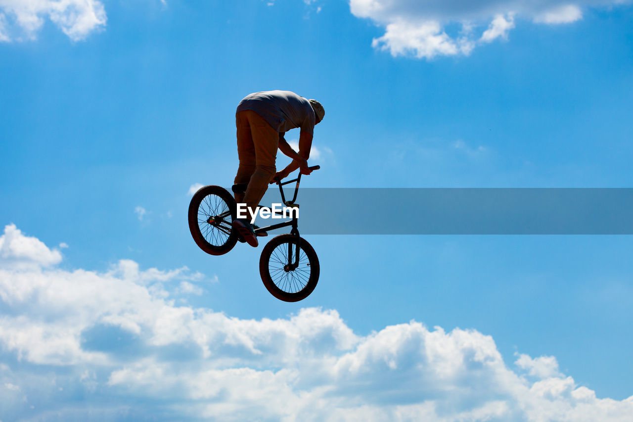 Low angle view of man with bicycle against sky