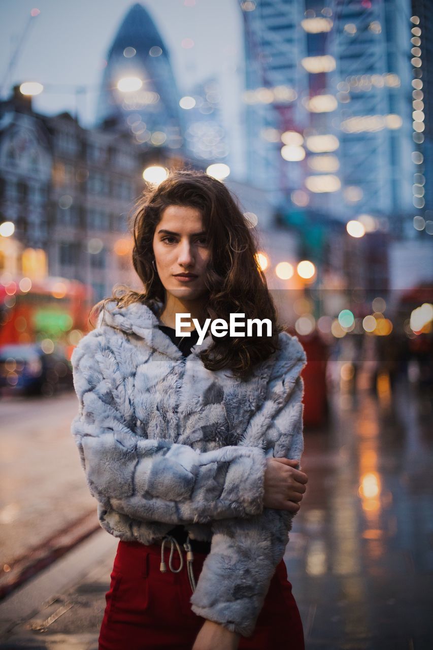 Portrait of woman wearing jacket standing on street in city