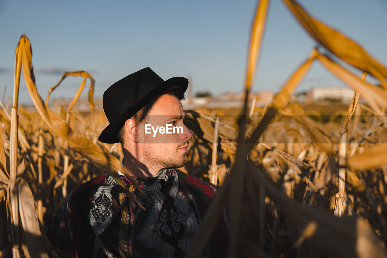 Male person wearing hat in a corn field, rural scene