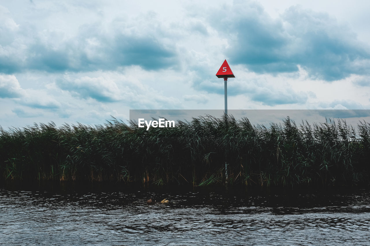 RED FLAG BY PLANTS AGAINST SKY