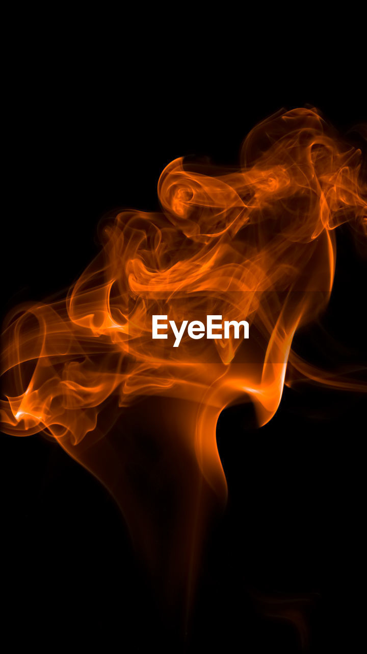 Close-up of orange smoke against black background