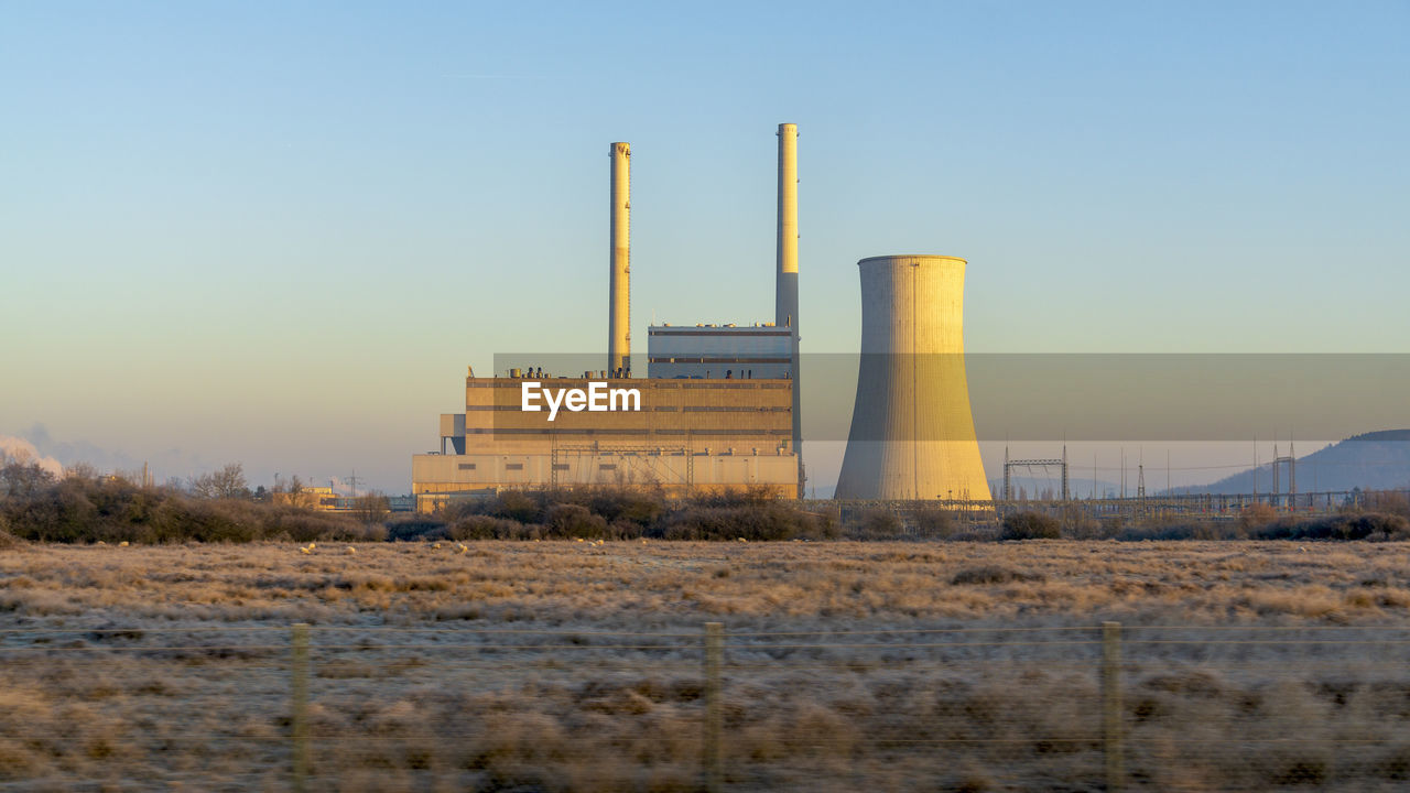 Nuclear reactor at industry against clear blue sky at sunset