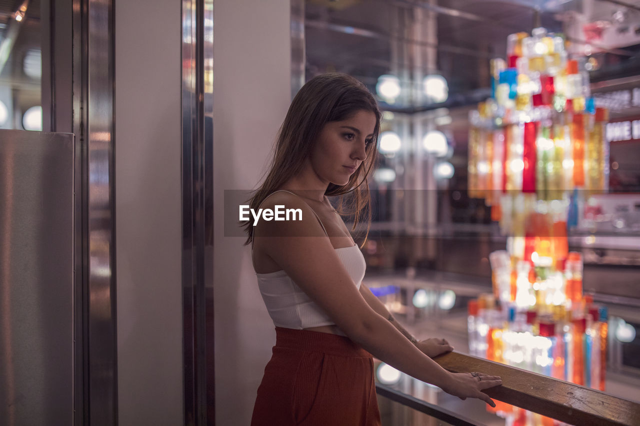 Young woman looking away while standing in shopping mall