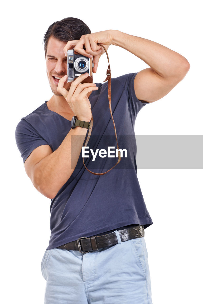 adult, white background, one person, casual clothing, arm, cut out, technology, portrait, men, studio shot, clothing, person, emotion, indoors, happiness, hand, young adult, listening, looking at camera, finger, standing, t-shirt, headphones, smiling, relaxation, holding, fun, music, positive emotion, activity, sleeve, cheerful, camera, front view, lifestyles, photo shoot, limb, three quarter length, arts culture and entertainment, occupation, jeans, facial expression, enjoyment, looking, glasses, human face, waist up, fashion