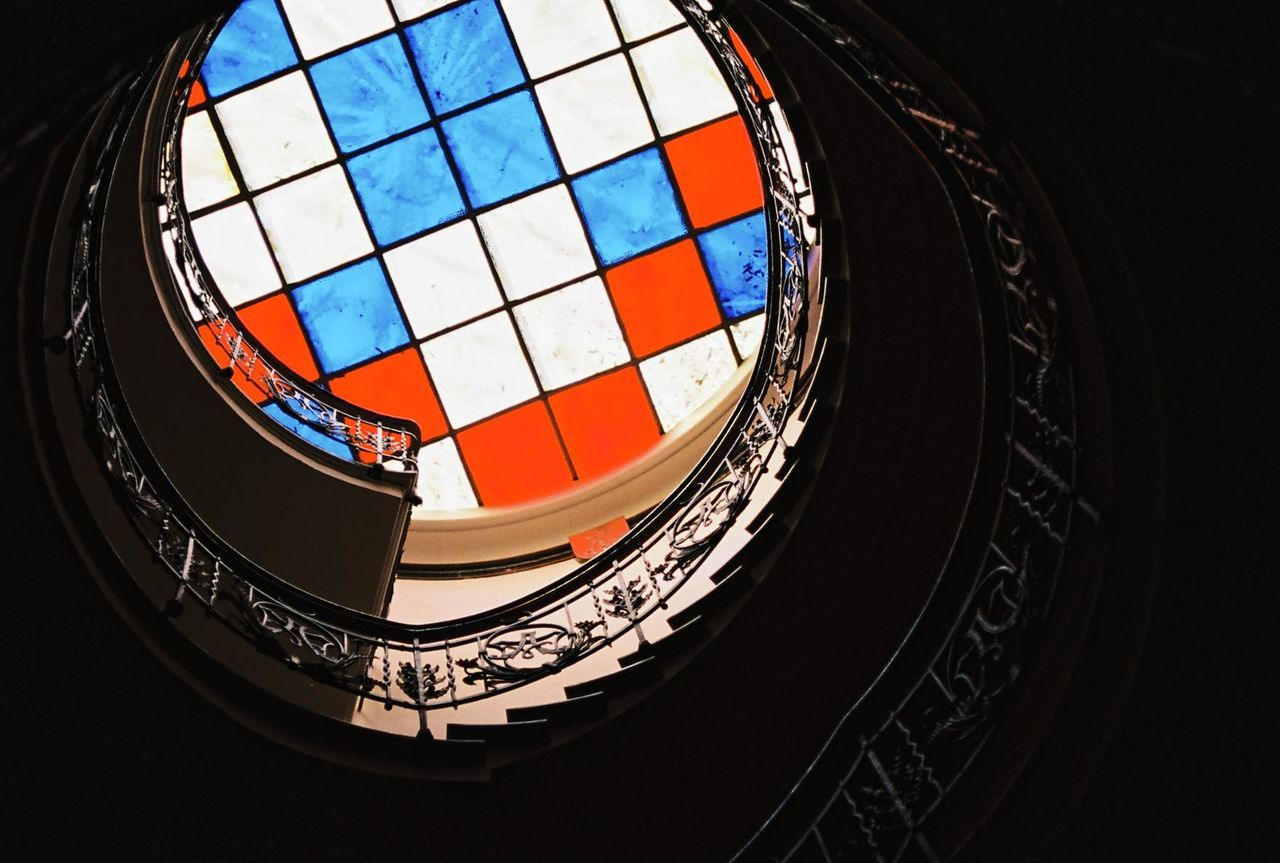 Low angle view of spiral staircase against multi colored skylight