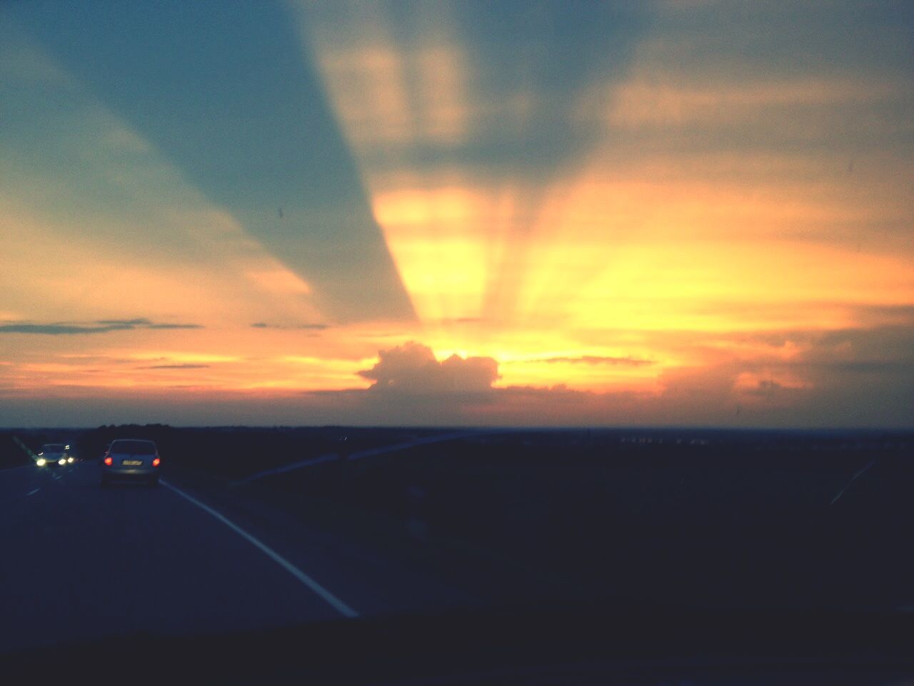 CARS ON ROAD AGAINST ORANGE SKY