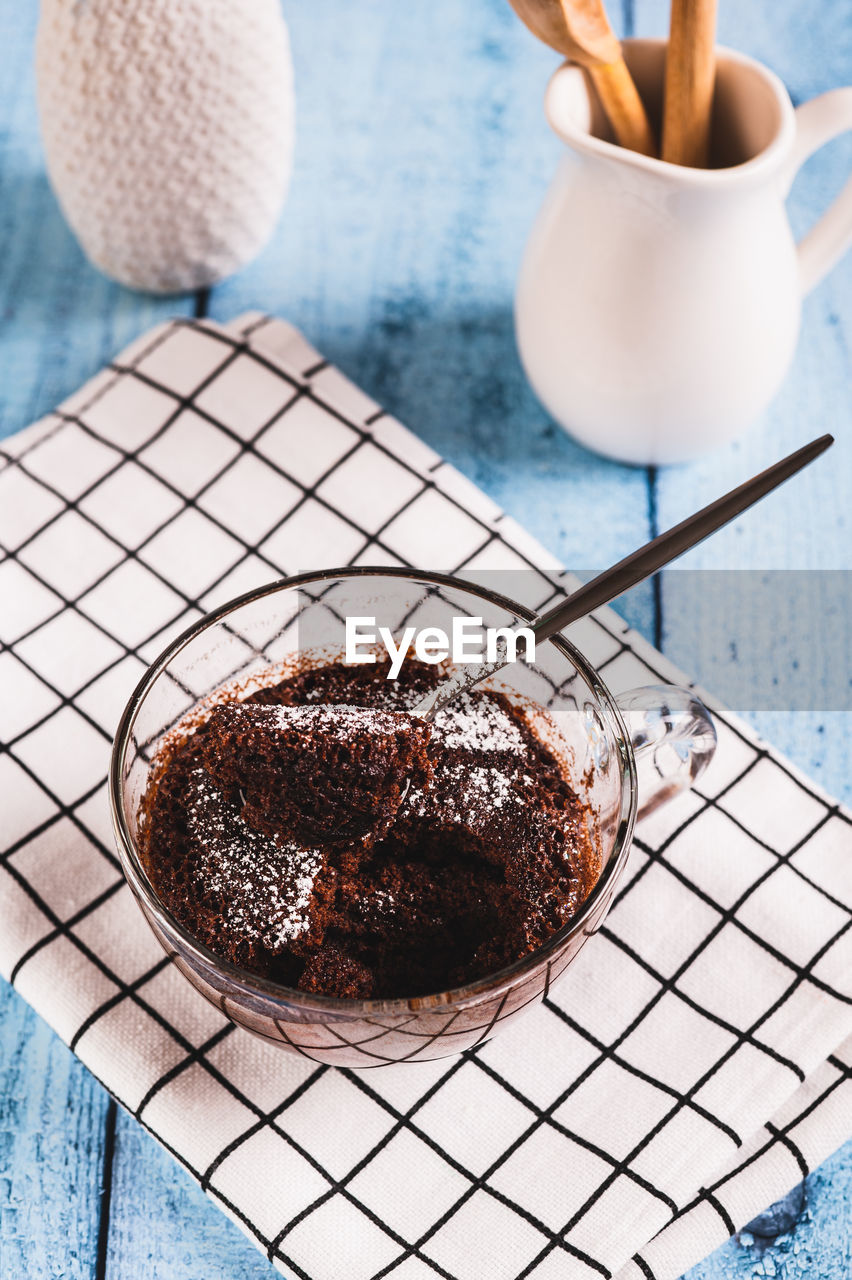 Homemade sweet cake in a mug made in the microwave on the table vertical view