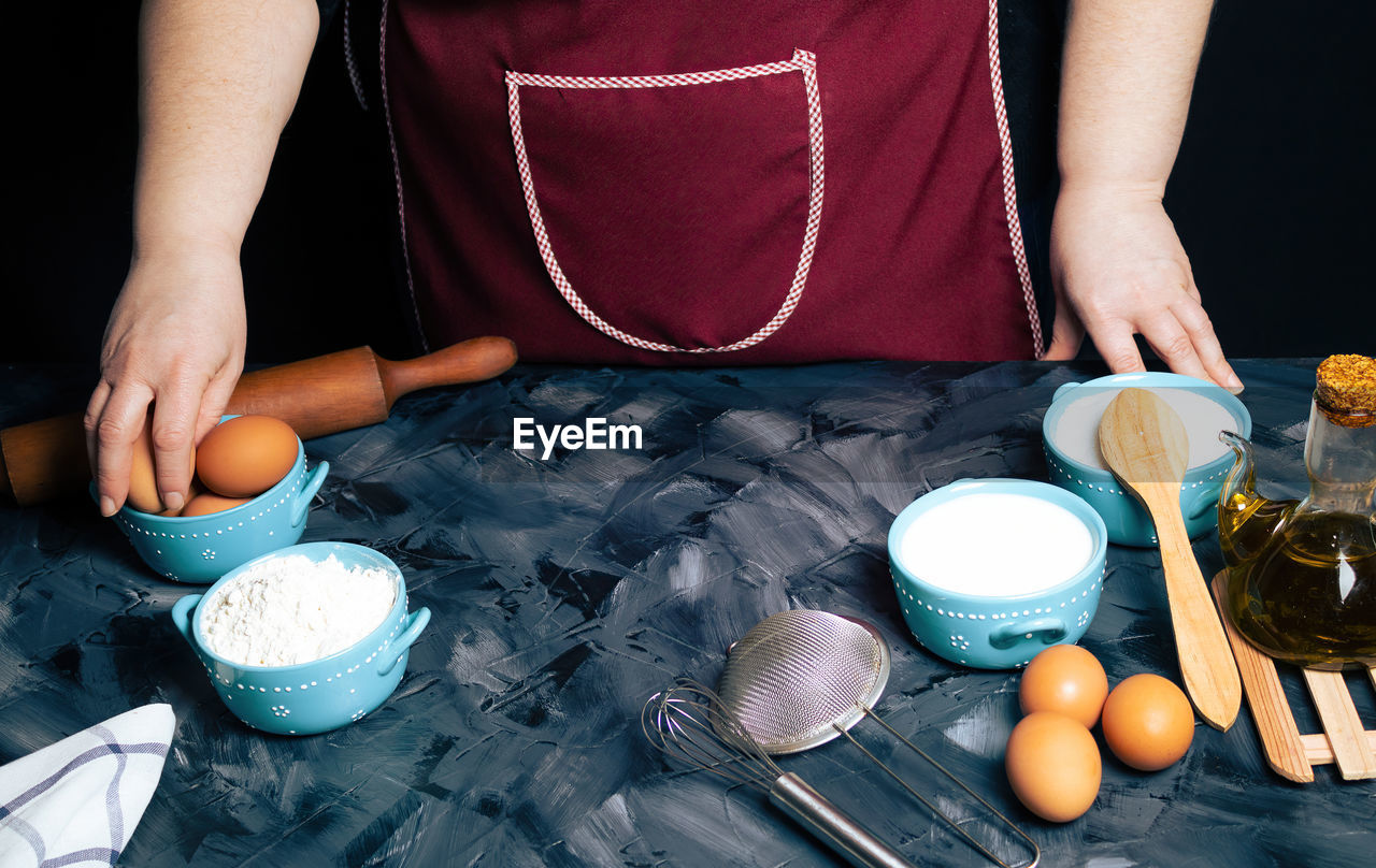 MIDSECTION OF WOMAN PREPARING FOOD IN KITCHEN