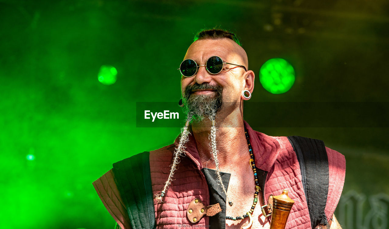 Low angle view of man wearing sunglasses while standing against stage lights