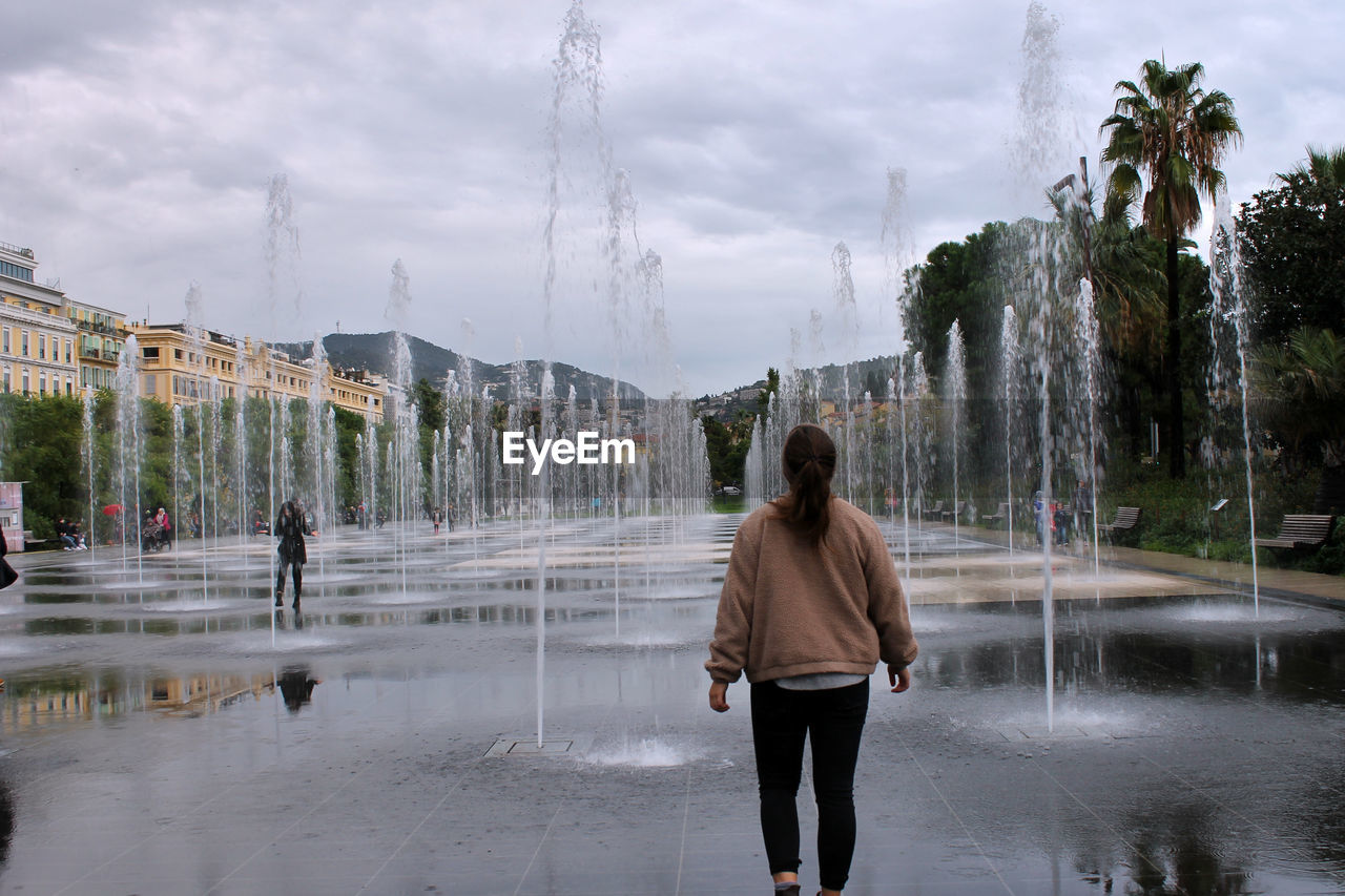 Rear view of woman walking at fountains 