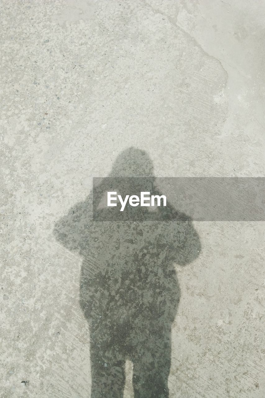 HIGH ANGLE VIEW OF MAN SHADOW ON SAND