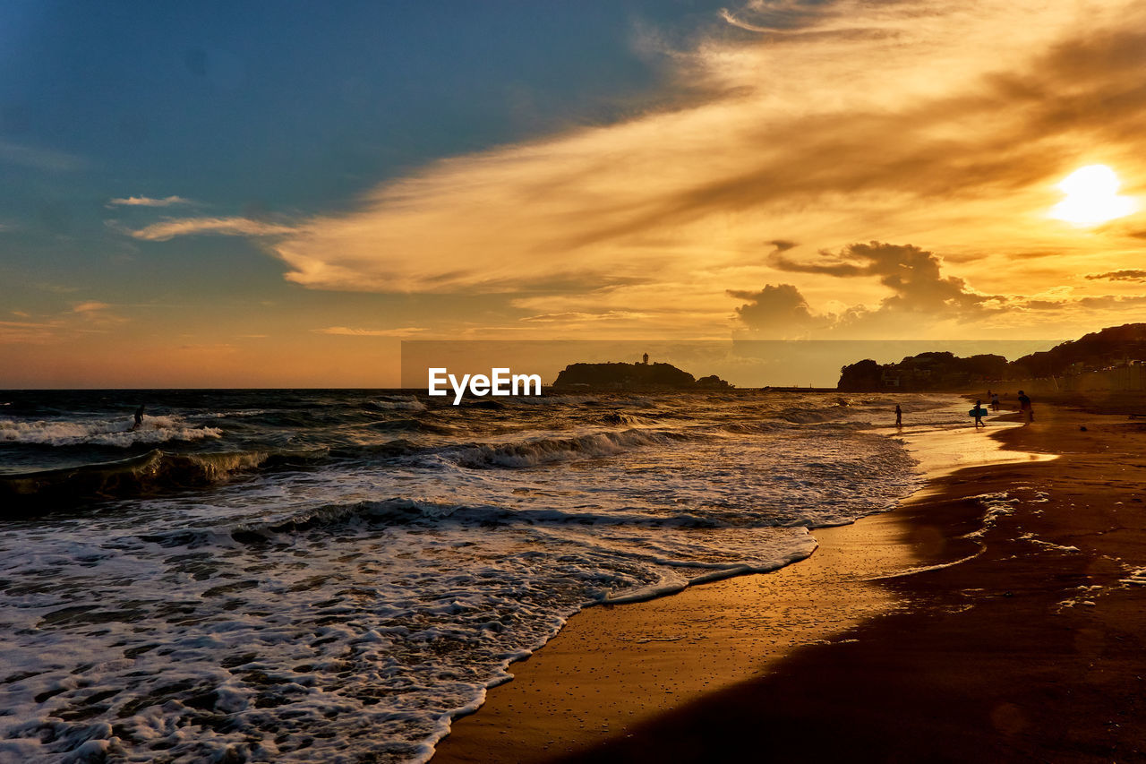 Scenic view of sea with silhouette people against sky during sunset