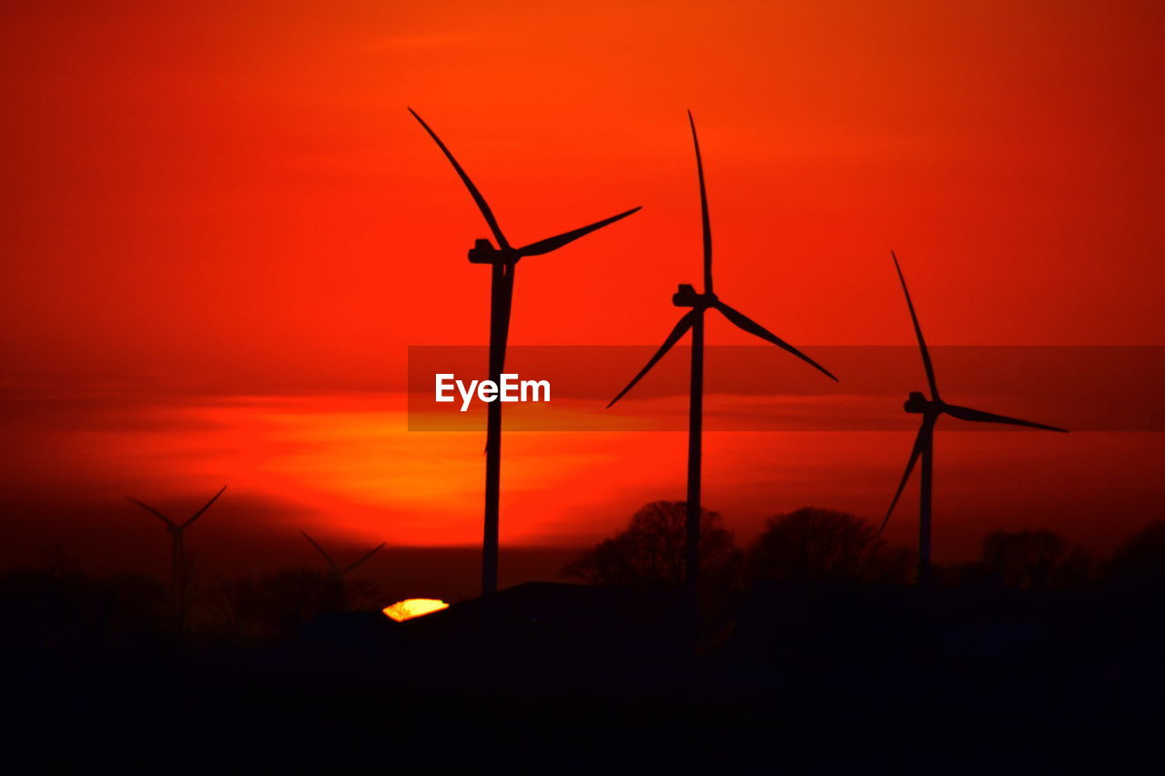 Silhouette windmills against sky during sunset