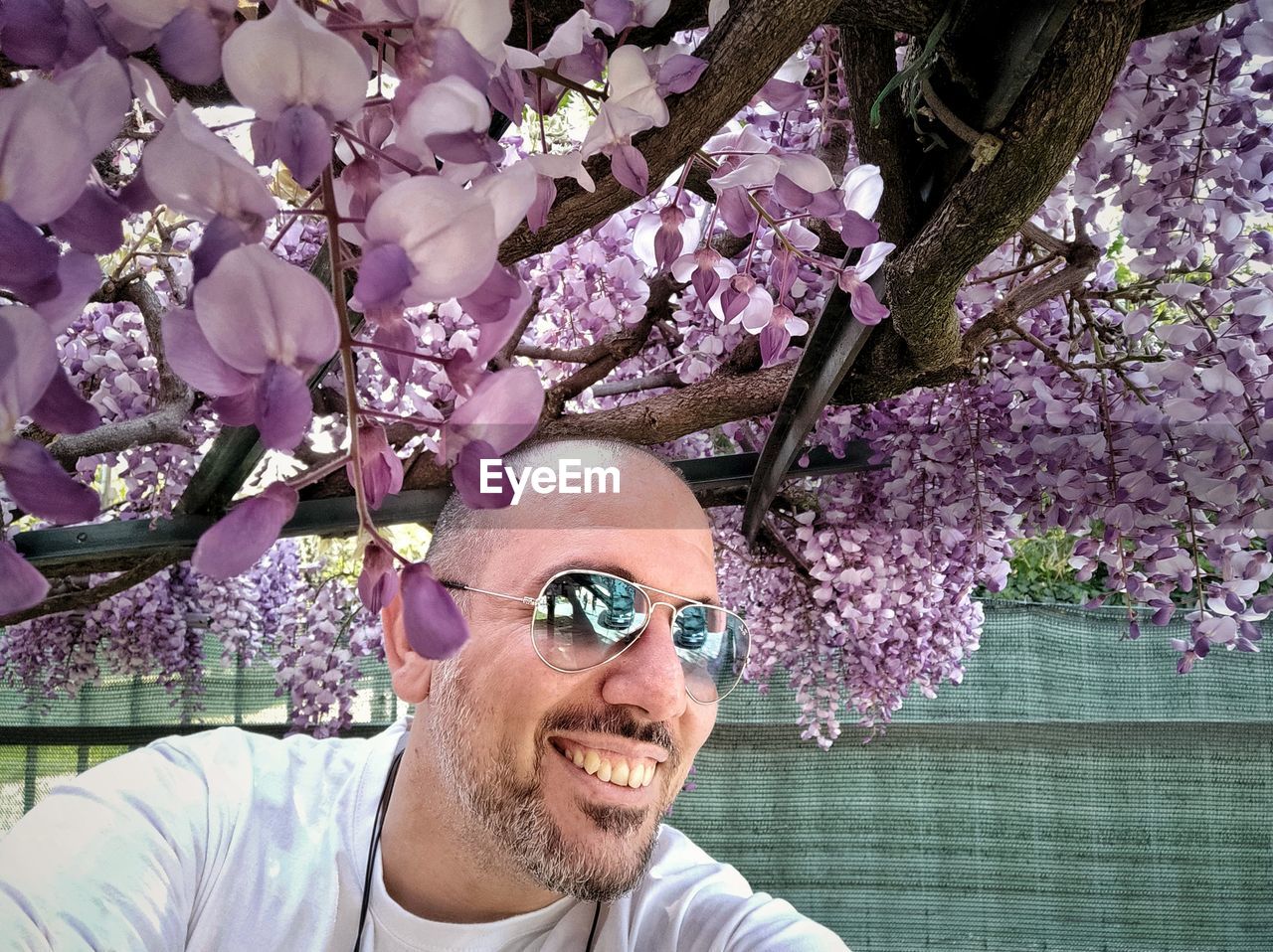 Close-up portrait of smiling young man with wisteria tree