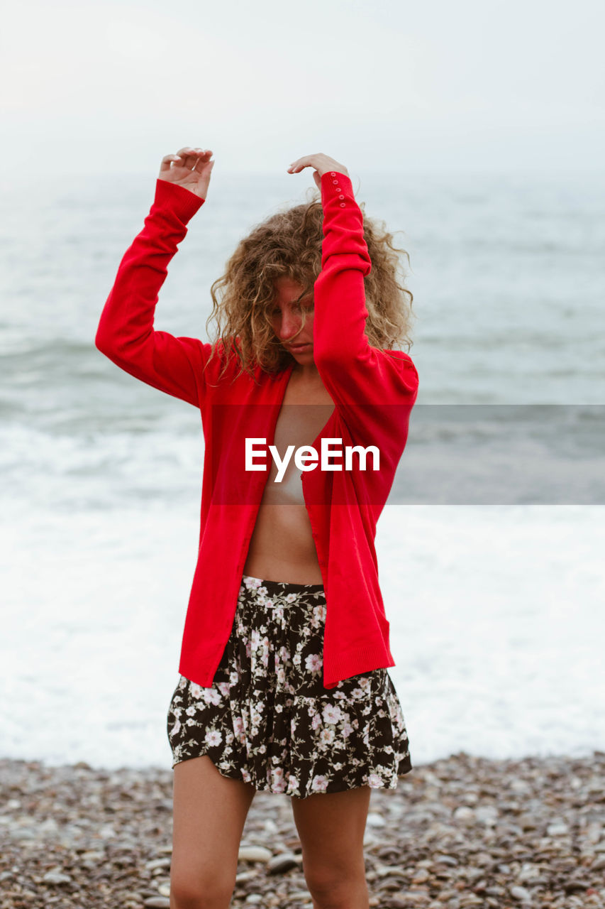 Woman wearing red jacket standing at beach