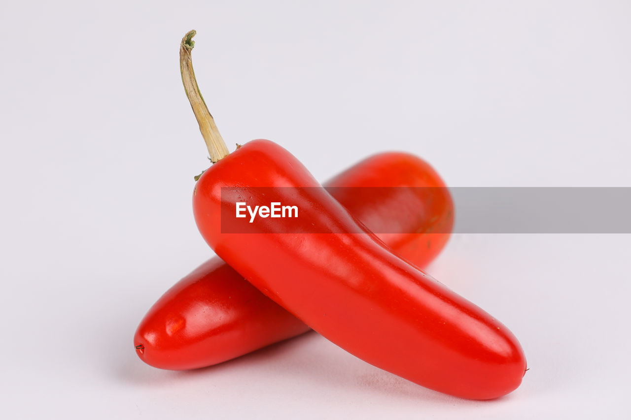 CLOSE-UP OF CHILI PEPPERS AGAINST WHITE BACKGROUND