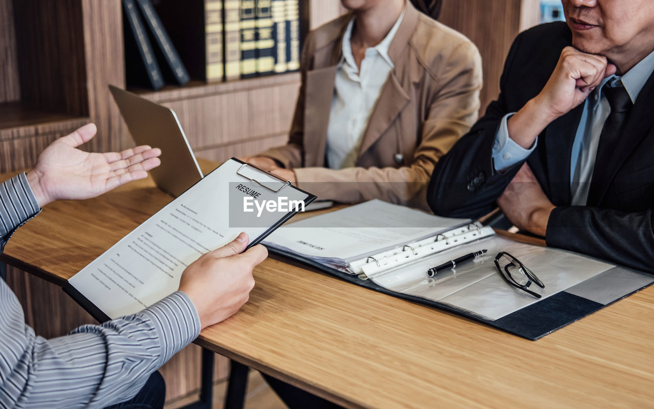 Midsection of man giving interview of business people in office