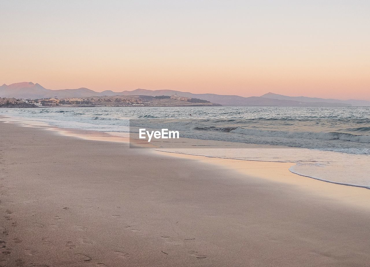 Scenic view of beach against clear sky during sunset