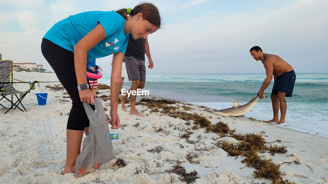 beach, land, sea, water, adult, sand, vacation, men, nature, holiday, two people, sky, leisure activity, trip, togetherness, lifestyles, women, full length, sports, ocean, coast, young adult, standing, day, body of water, travel, friendship, bending, clothing, summer, female, fun, shore, casual clothing, outdoors, bonding, person, activity, motion