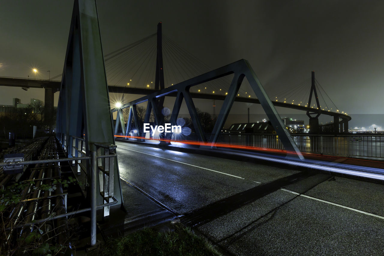 Illuminated bridge over river against sky in city at night