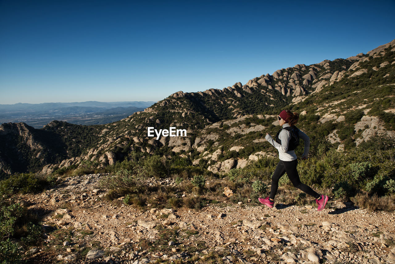 Woman runs through the mountains of montserrat in catalonia, spain.