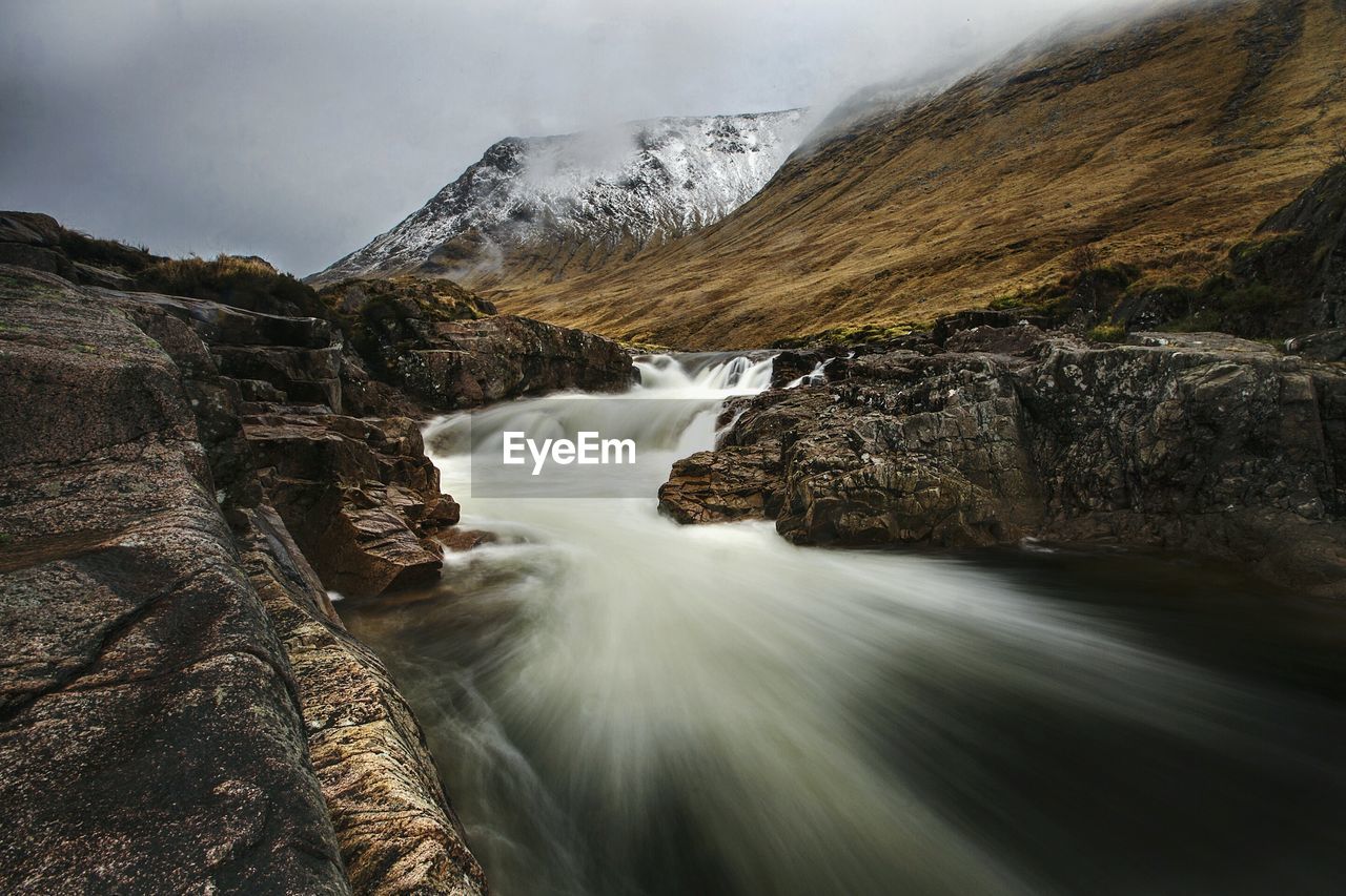 Scenic view of waterfall against mountains