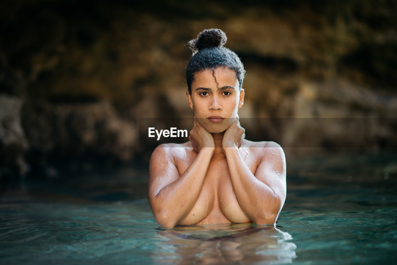 Portrait of shirtless woman standing in sea