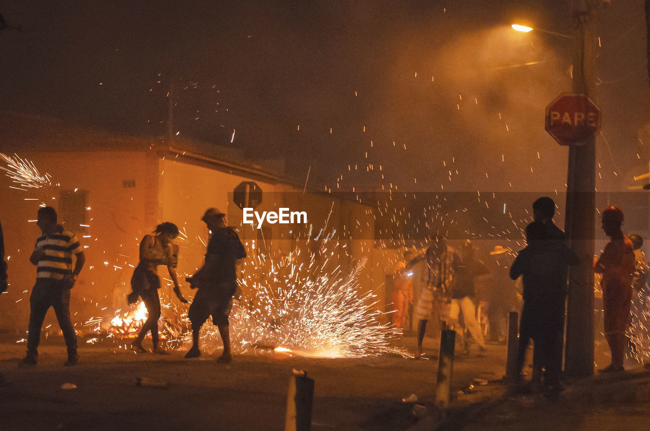 Group of people burning firework in city at night