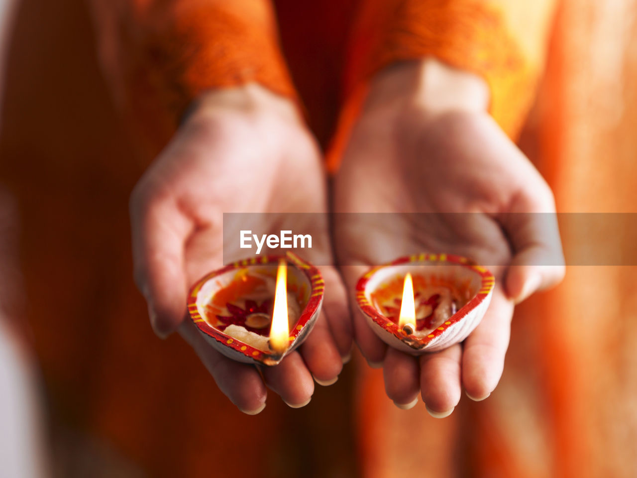 Midsection of woman holding diyas