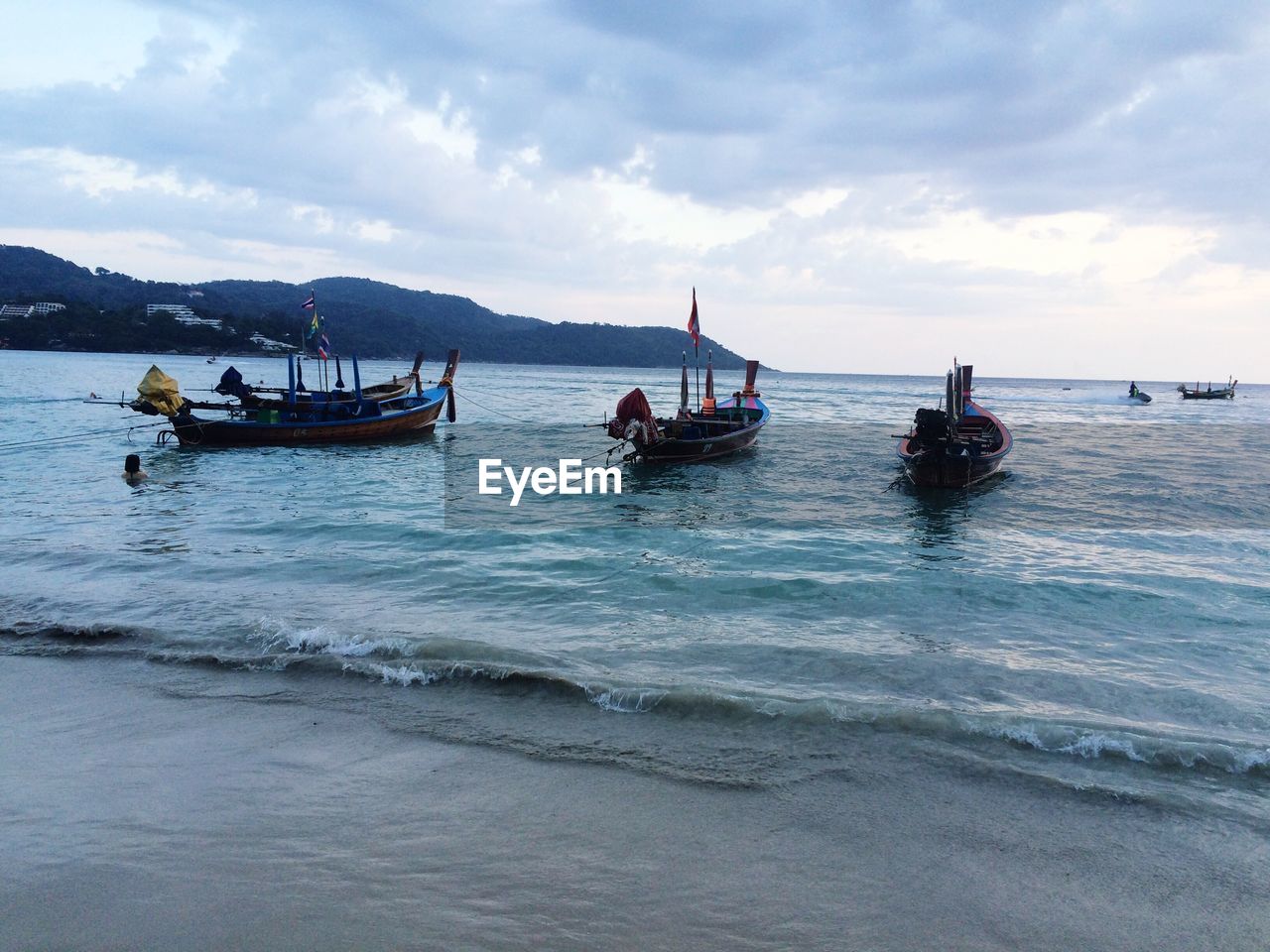 Boats in sea against cloudy sky