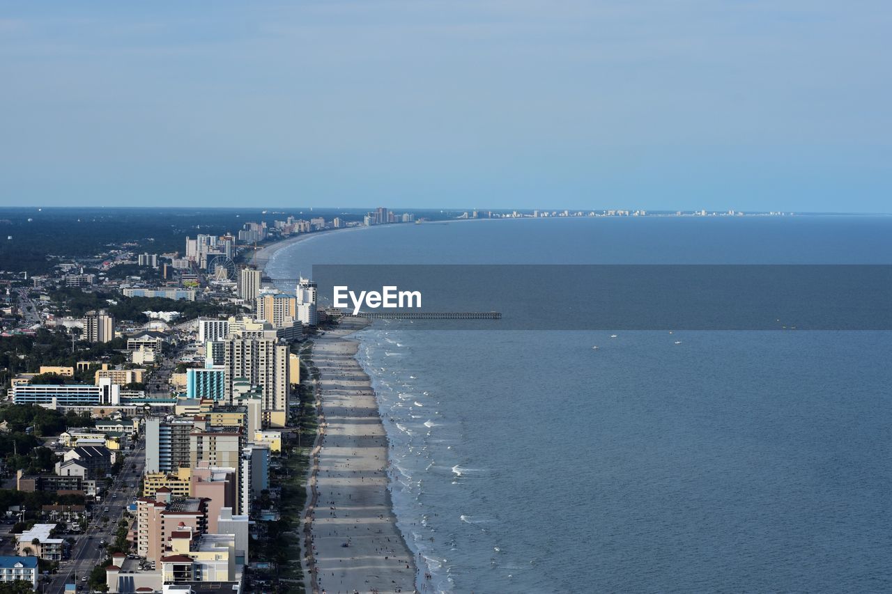 Aerial view of cityscape by sea against clear sky