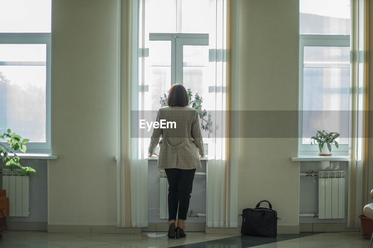 Unrecognizable professional businesswoman in office hall. standing at work lobby looking at window.