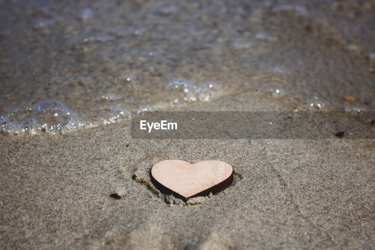 CLOSE-UP OF HEART SHAPE ON SAND AT BEACH