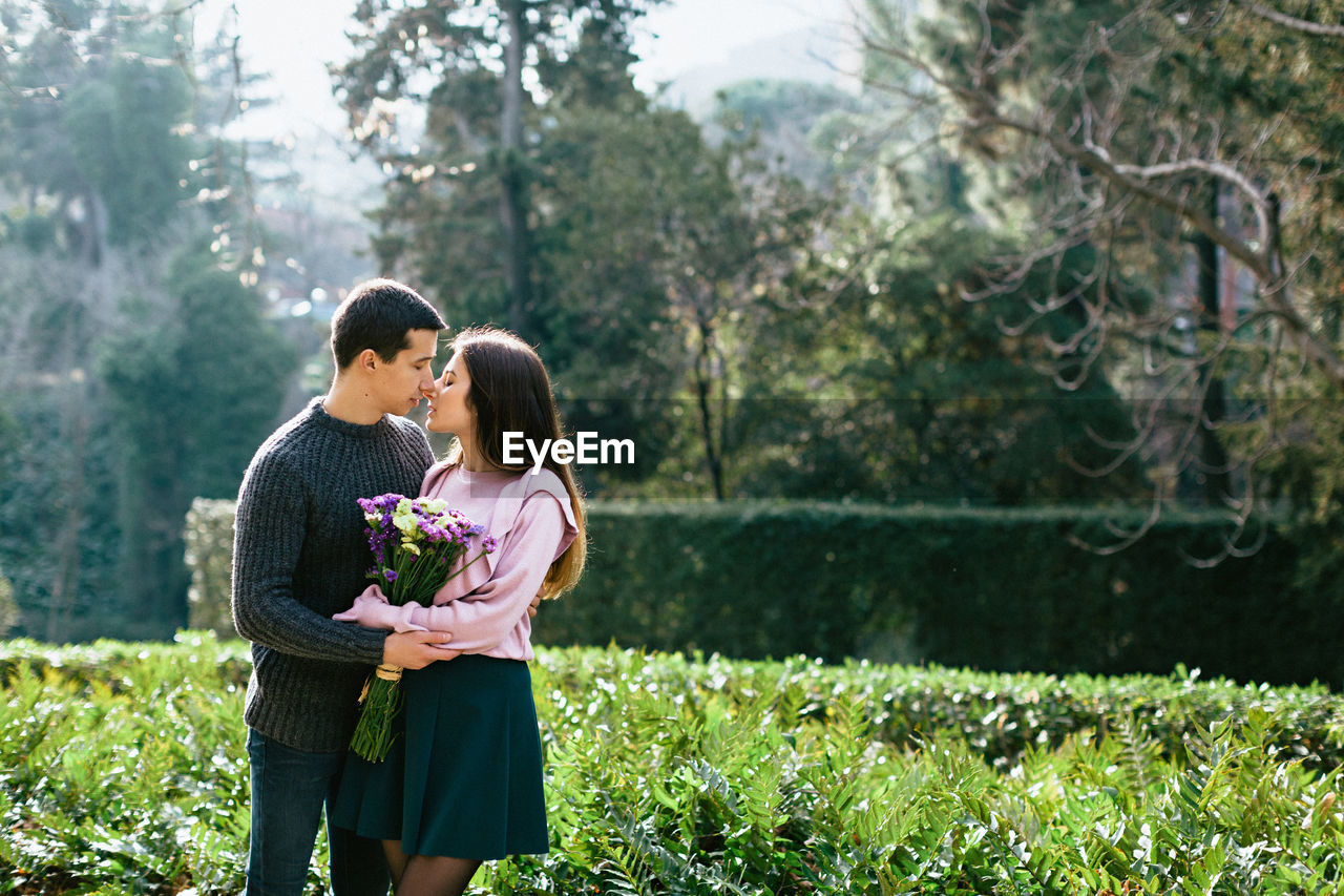 Couple kissing while standing against plants in park
