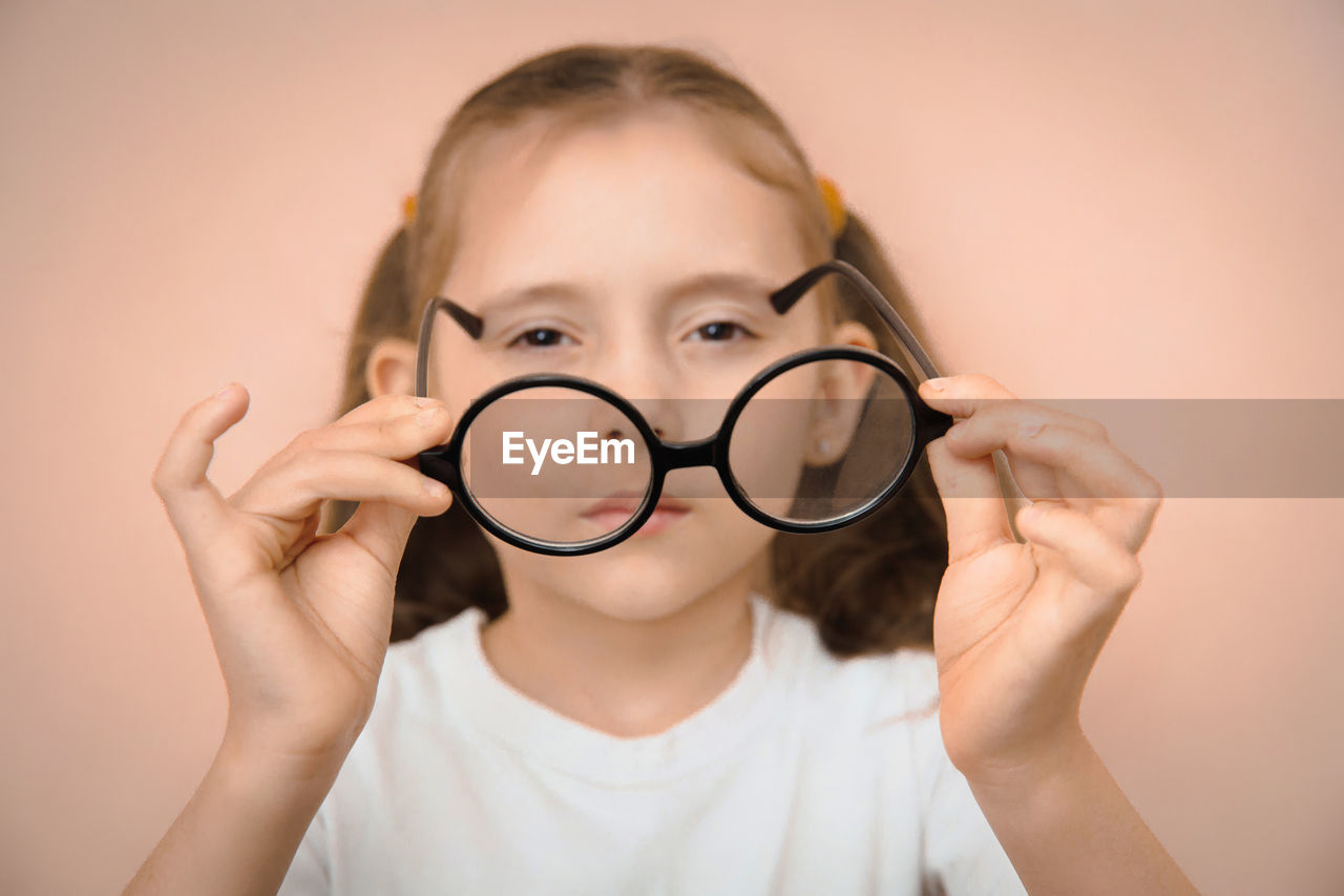 vision care, glasses, childhood, child, eyewear, nose, human face, one person, human head, eyeglasses, portrait, human eye, moustache, indoors, human hair, studio shot, human mouth, fun, cute, hairstyle, front view, female, women, colored background, eye, looking at camera, smiling, toddler, humor, happiness, close-up, headshot, skin, education, holding, cheerful, emotion, intelligence, looking through an object, person