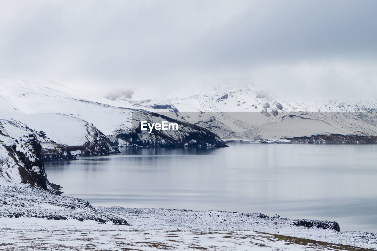 SCENIC VIEW OF LAKE BY SNOWCAPPED MOUNTAINS AGAINST SKY DURING WINTER