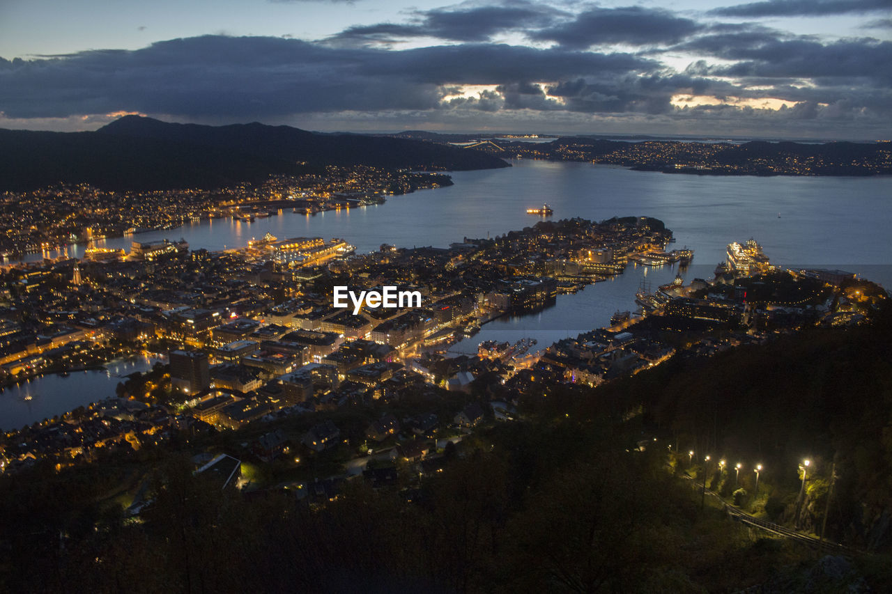 High angle view of illuminated city by sea against sky