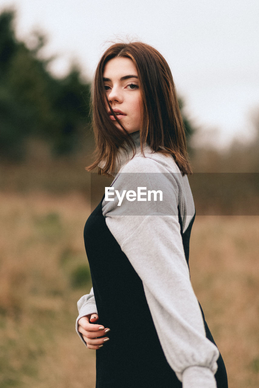 YOUNG WOMAN STANDING ON FIELD