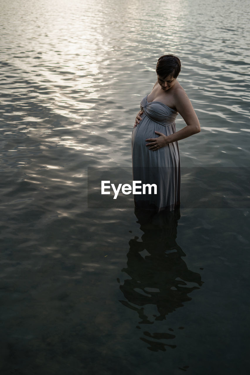 WOMAN STANDING IN LAKE AT SHORE