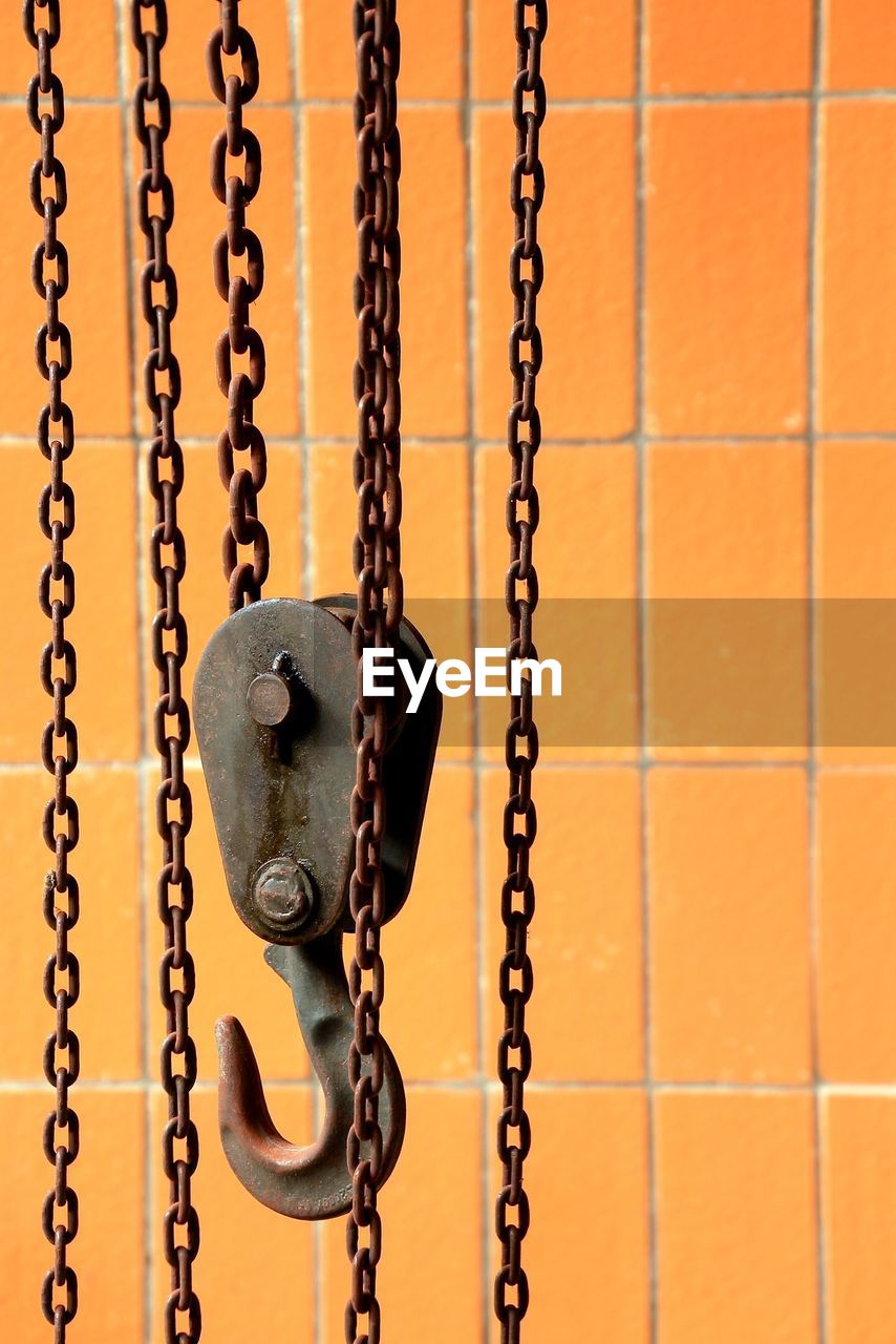 Close-up of metal hook against orange wall