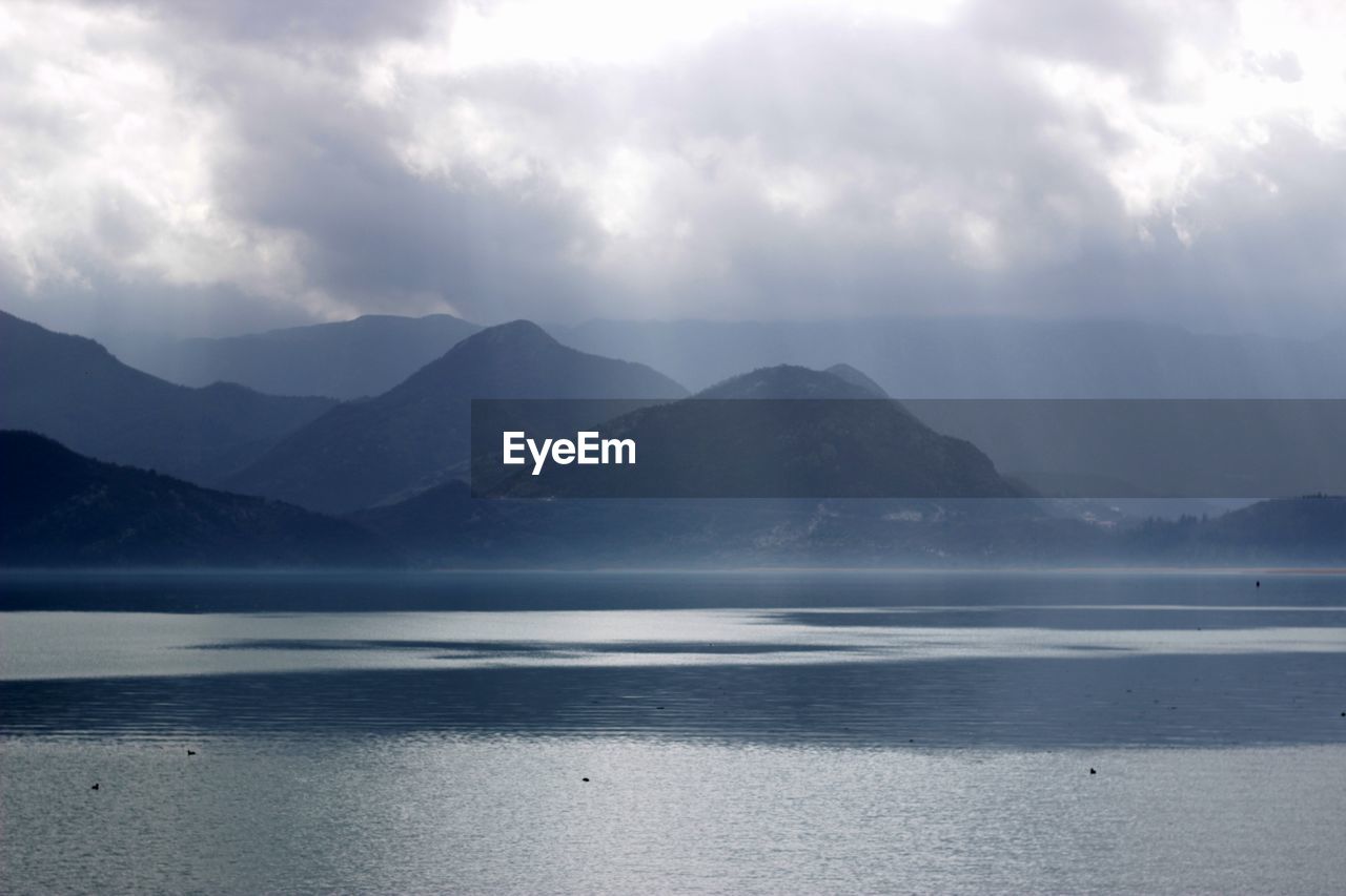 Scenic view of sea and mountains against sky