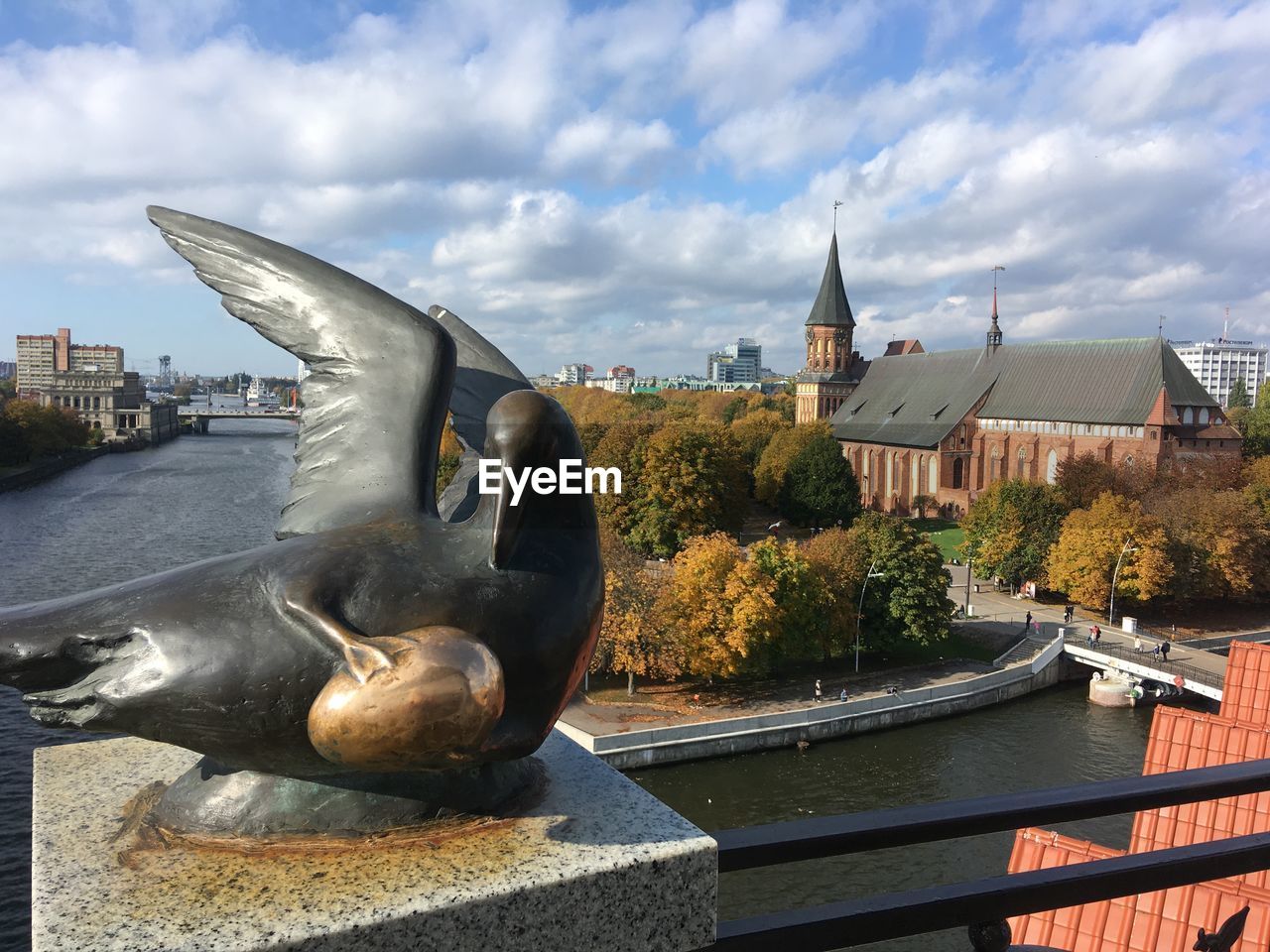 Statue by river against buildings in city